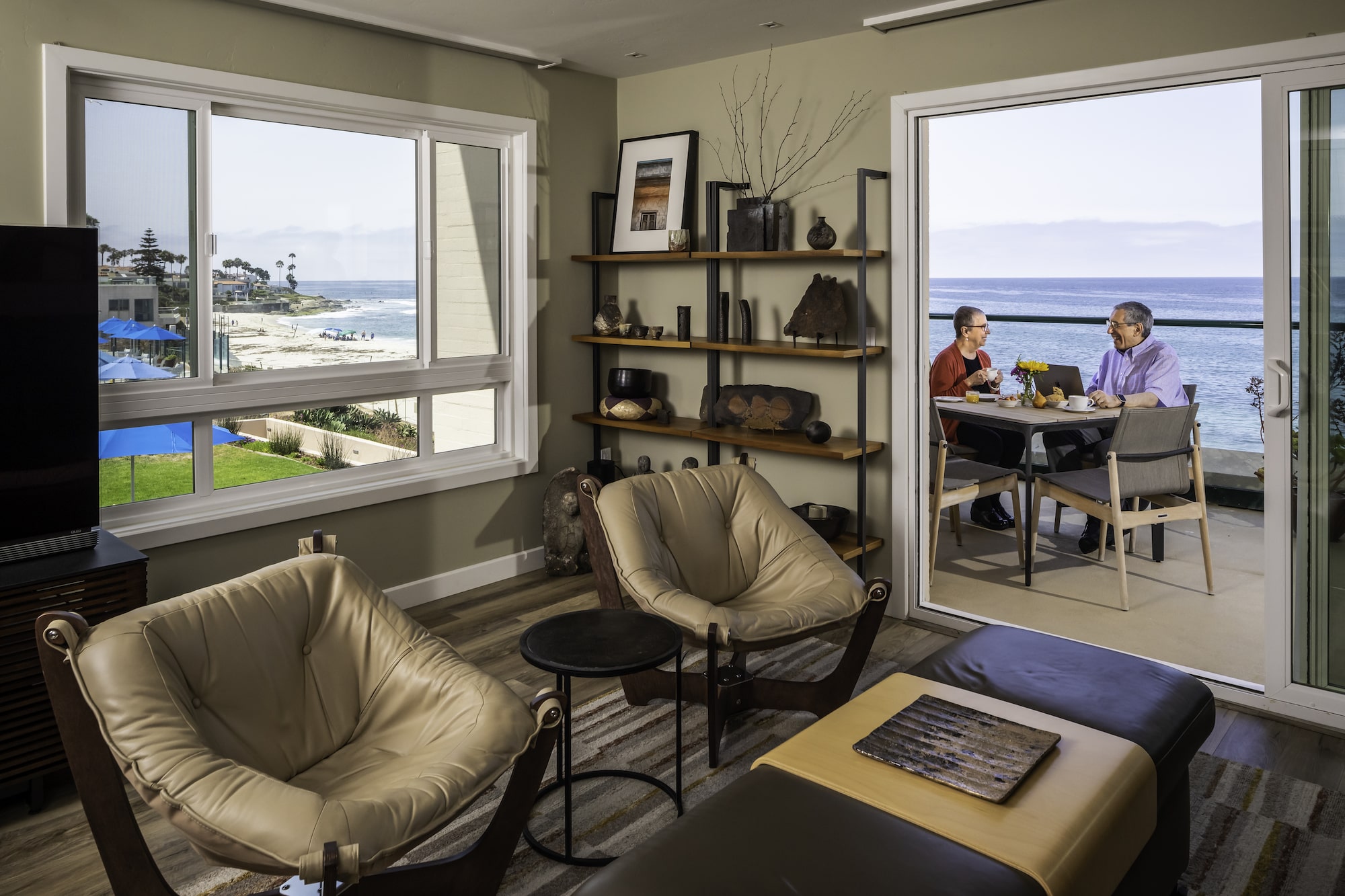 Living room with couple on balcony in background	